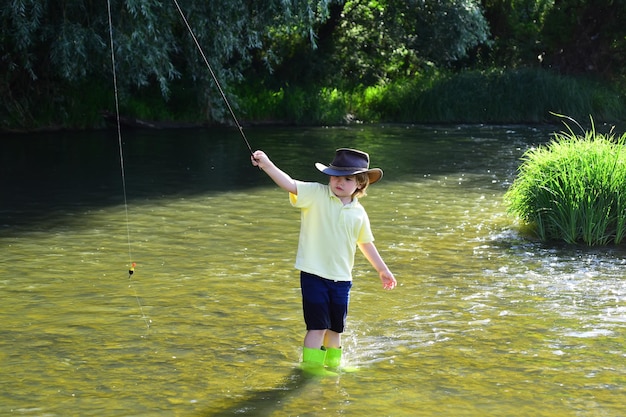 Pequeno pescador pronto para pescar Menino pescando em um rio da floresta Menino peixe na lagoa Menino pescador com vara de pescar