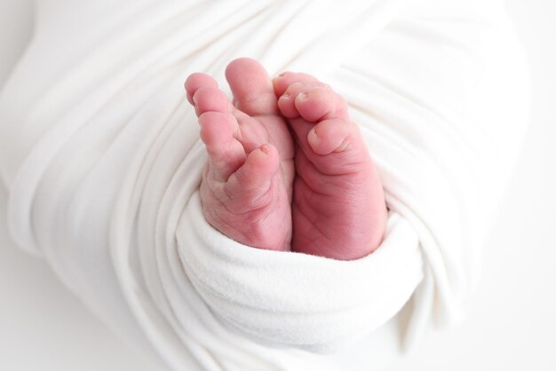 El pequeño pie de un bebé recién nacido Los pies suaves de un recién nacido en una manta blanca Un primer plano de los dedos de los pies, los talones y los pies de un recién nacido Fotografía macro