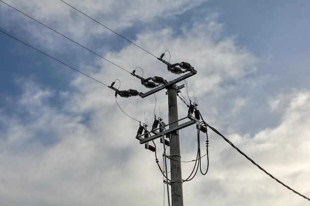 Pequeno pilar de concreto com linhas elétricas, céu com nuvens no fundo.