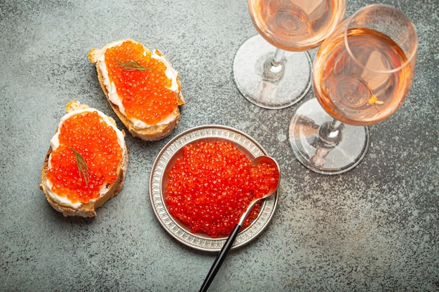 Foto pequeno prato de metal com caviar de salmão vermelho duas torradas de caviar.