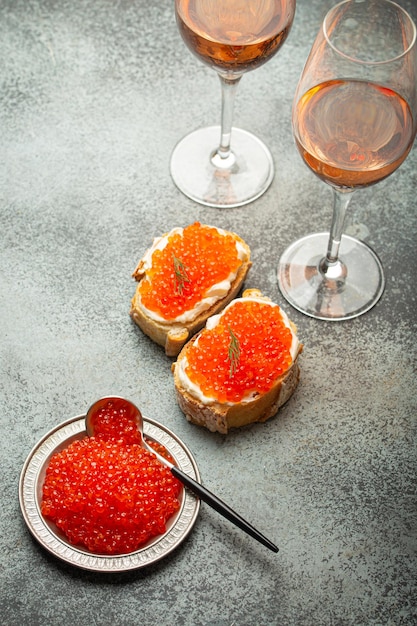 Pequeno prato de metal com caviar de salmão vermelho duas torradas de caviar