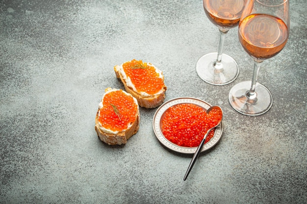 Pequeno prato de metal com caviar de salmão vermelho duas torradas de caviar