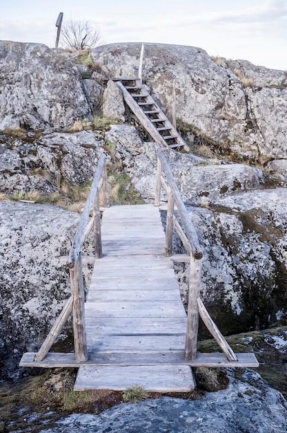 Pequeño puente y escaleras de madera viejos en una isla rocosa