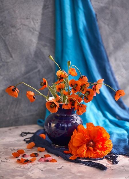 Un pequeño ramo de amapolas rojas en jarrón de cerámica azul