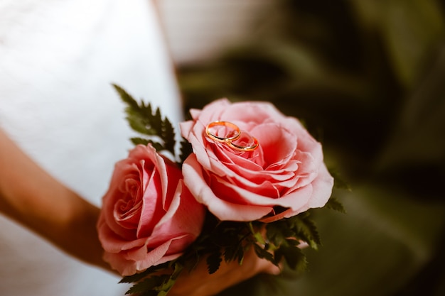 Pequeño ramo de rosas rosadas con anillos de boda en la parte superior. Concepto del día de la boda