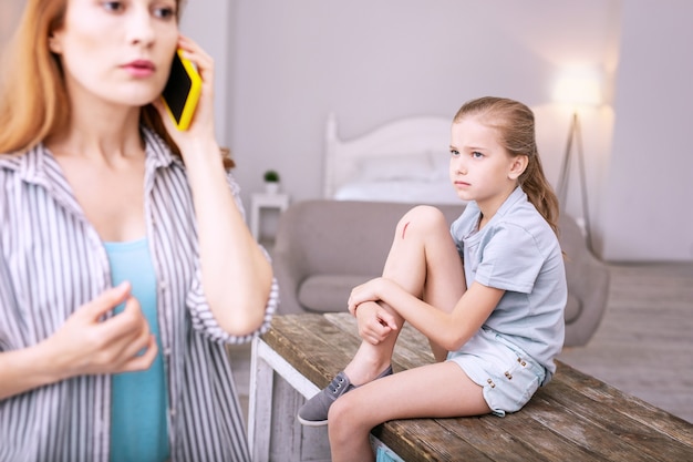 Pequeño rasguño. Triste niña triste mirando a su madre mientras tiene un rasguño en la pierna