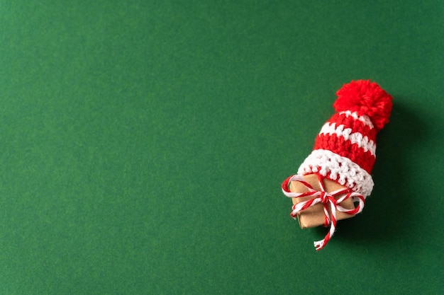 Pequeño regalo con gorro rojo de santa sobre fondo verde con espacio de copia Vista superior