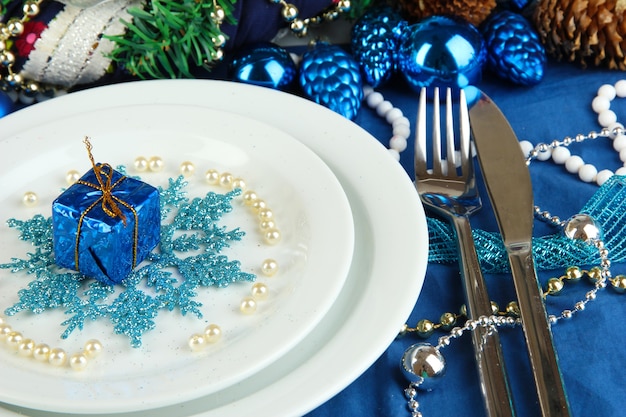 Pequeño regalo de Navidad en la placa para servir la mesa de Navidad en primer plano de tono azul
