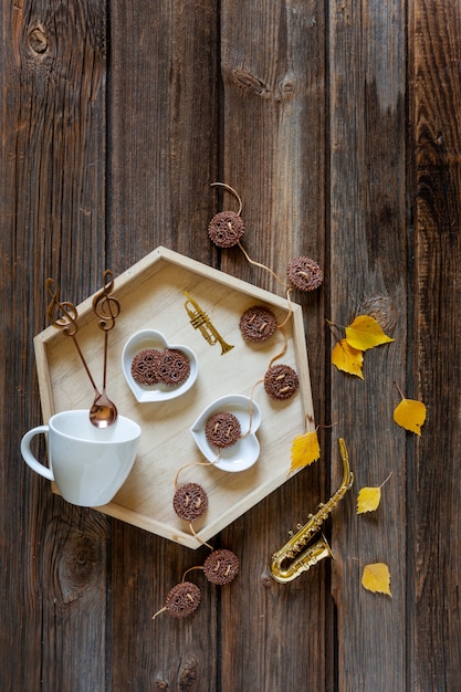 Pequeño saxofón dorado y hojas de otoño y una bandeja con taza y galleta. Otoño