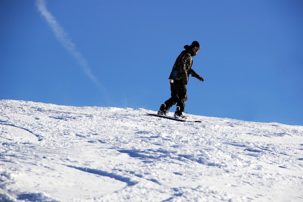 Pequeño snowboarder sobre fondo de cielo azul.