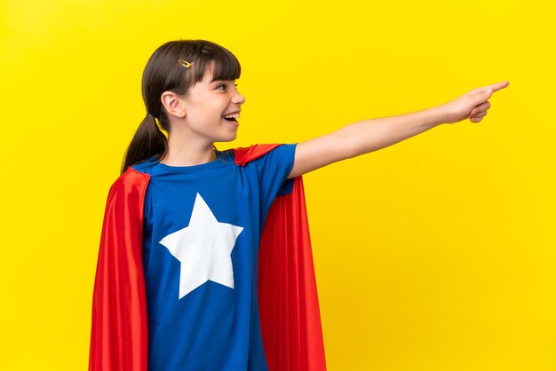 Pequeño super héroe niño aislado sobre fondo púrpura apuntando hacia fuera