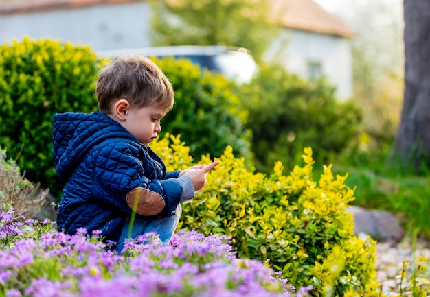 Pequeño todler jugando con flores en el jardín