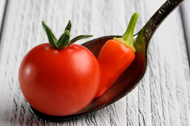 Foto pequeño tomate rojo maduro con pimiento rojo picante