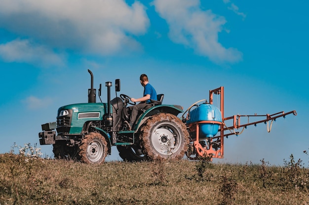 Un pequeño tractor en el fondo del cielo cultiva el campo antes de arar el
