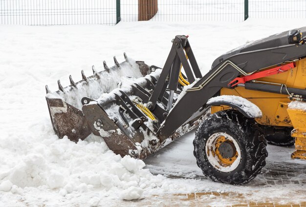 Un pequeño tractor quita la nieve de la carretera cerca de la casa.