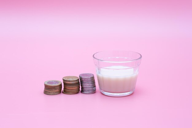 Pequeño vaso de leche con monedas alrededor