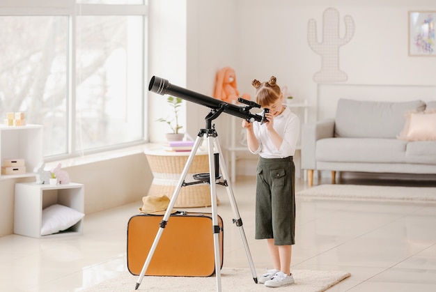 Pequeño viajero lindo con telescopio en casa