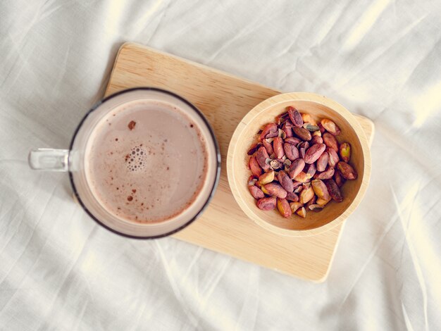 Pequeños aperitivos conjunto de frijoles salados y chocolate caliente servido en la cama