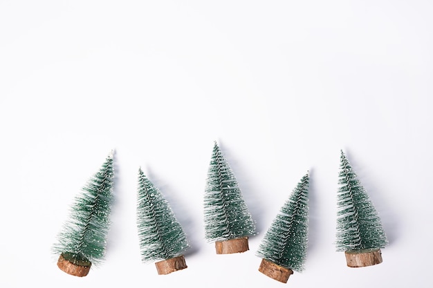 Pequeños árboles de Navidad decorados en fondo blanco con espacio de copia