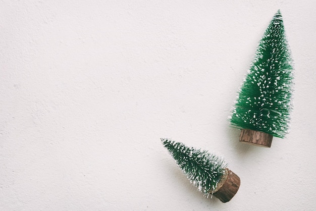 Pequeños árboles de Navidad decorativos con decoración de Año Nuevo en la vista superior de fondo de masilla blanca