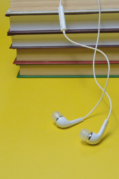 Foto pequeños auriculares blancos y pila de libros concepto de audiolibro.