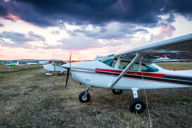 Pequeños aviones privados estacionados en el aeródromo al atardecer escénico