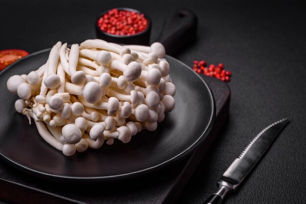 Foto pequenos cogumelos de faixa brancos comestíveis com sal e especiarias em um fundo plano