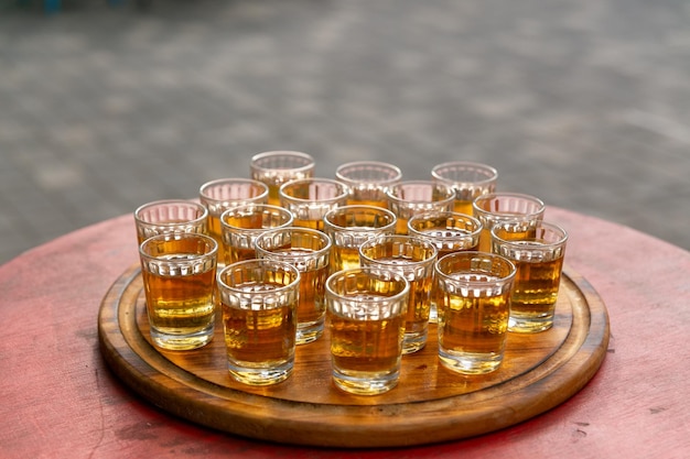 Pequenos copos cheios de conhaque em uma bandeja de madeira Bufê alcoólico no café da rua Shots com bebida alcoólica a gosto