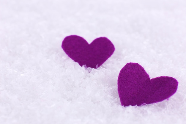 Pequenos corações de feltro no fundo nevado