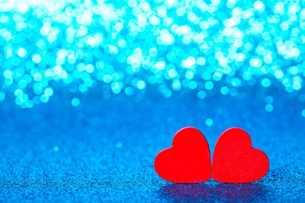 Foto pequeños corazones decorativos rojos contra brillo azul brillante con increíbles luces bokeh.