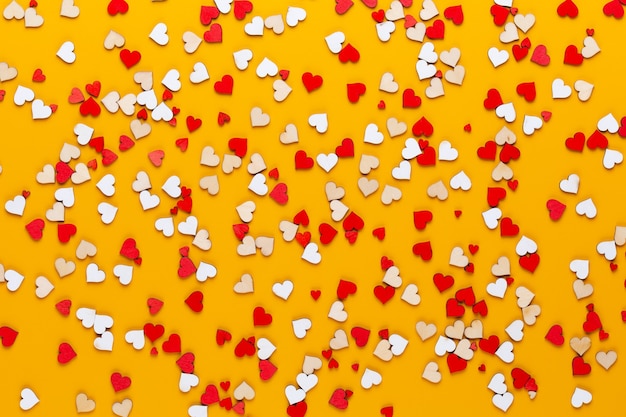 Foto pequeños corazones de madera sobre un amarillo una idea creativa. tarjeta de felicitación del día de san valentín.