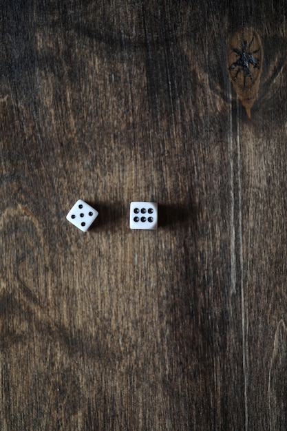 Pequeños dados blancos sobre una mesa de textura de madera marrón