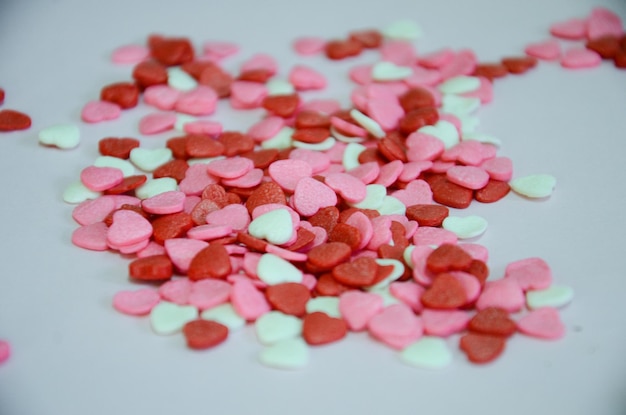 Pequeños dulces blancos, rosas y rojos en forma de corazón para decorar una tarta de cumpleaños