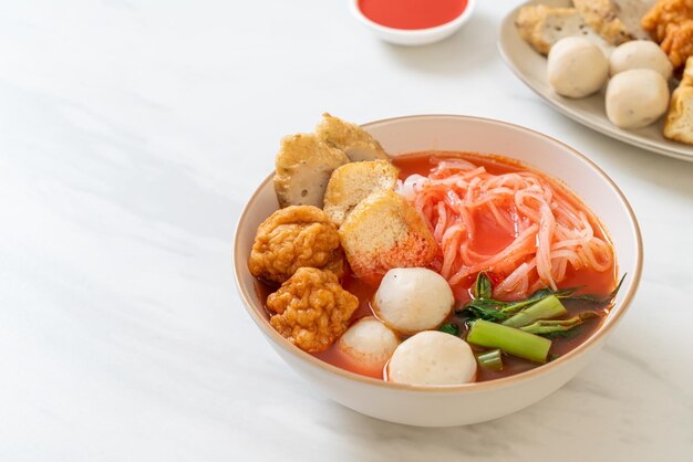 Foto pequeños fideos de arroz planos con bolas de pescado y bolas de camarón en sopa rosa yen ta four o yen ta fo