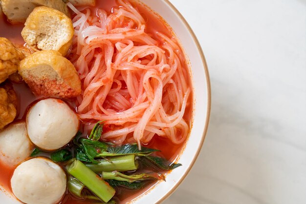 Foto pequeños fideos de arroz planos con bolas de pescado y bolas de camarón en sopa rosa yen ta four o yen ta fo