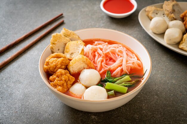 Foto pequeños fideos de arroz planos con bolas de pescado y bolas de camarón en sopa rosa yen ta four o yen ta fo