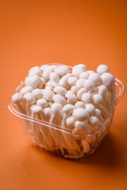 Foto pequeños hongos de haya blancos comestibles con sal y especias sobre un fondo plano
