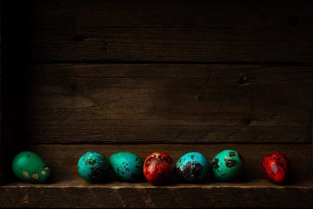 Pequeños huevos de Pascua de codorniz teñidos en rústico de madera oscura.