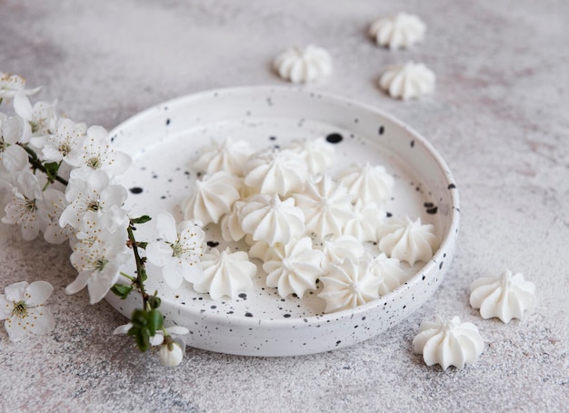 Foto pequenos meringues brancos na tigela de cerâmica em fundo de concreto