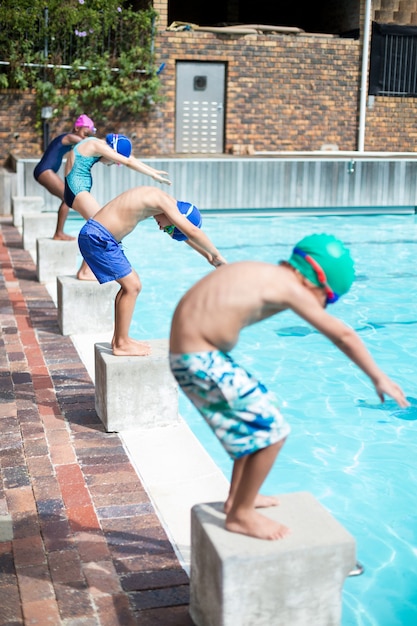 Pequenos nadadores se posicionando para pular na piscina