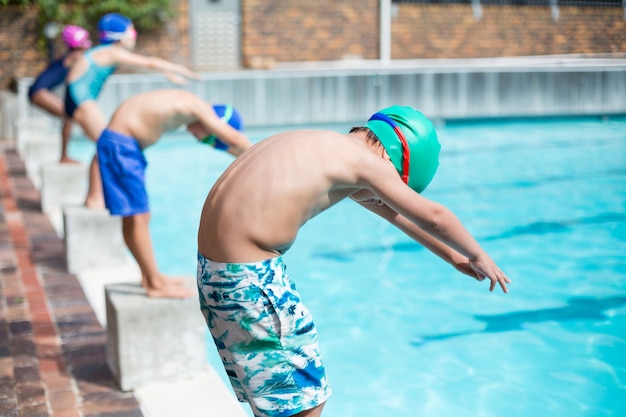 Pequenos nadadores se preparando à beira da piscina em um dia ensolarado