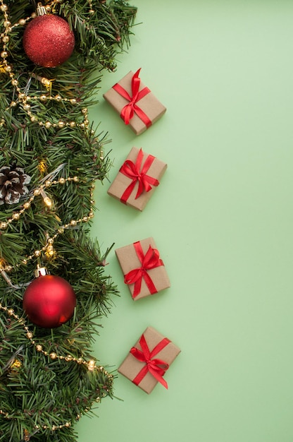 Pequeños obsequios con cintas rojas sobre fondo verde con decoración navideña