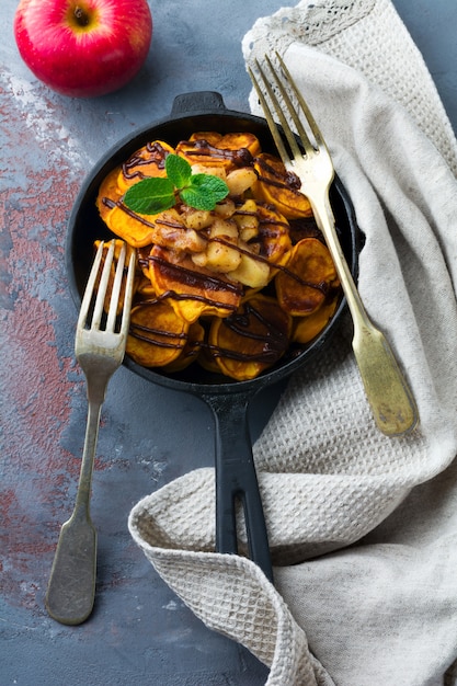 Pequeños panqueques de calabaza con salsa de chocolate en una sartén en el fondo vintage.