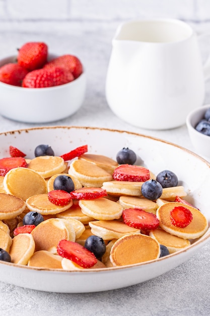 Pequeños panqueques con fresas y arándanos para el desayuno. Enfoque selectivo.