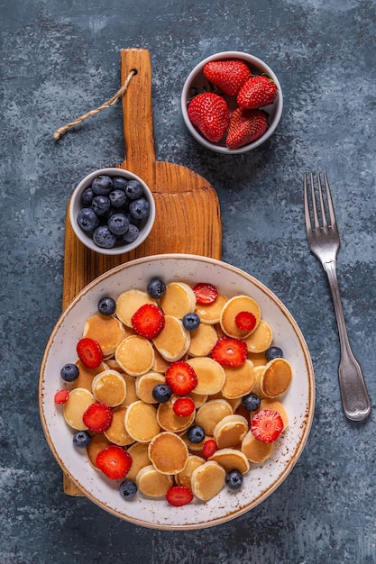 Pequeños panqueques con fresas y arándanos para el desayuno. Vista superior.