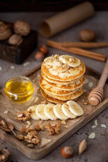 Pequeños panqueques con plátano, nueces y miel en una bandeja de madera