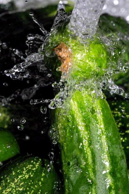 Pequenos pepinos verdes são lavados sob um fluxo de macro fotografia de close-up de água limpa