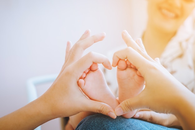 Pequenos pés de bebês recém-nascidos nas mãos femininas em forma de coração conceito de família feliz