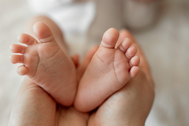 Pequeños pies de un bebé en manos de la madre Amor en la familia Valor familiar El amor de una madre por un niño recién nacido El concepto de una infancia feliz