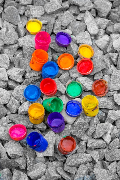 Pequenos potes de tinta coloridos podem repousar em um close-up de seixo cinza